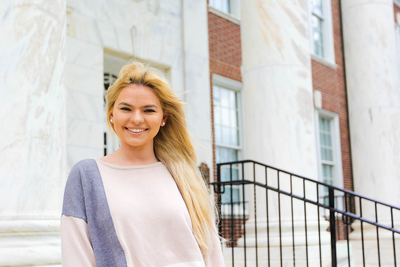 Caitlyn smiles and stands on the steps of Bunce Hall.