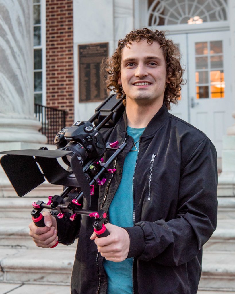 Adam holding his video gear and looking at the camera at Bunce.