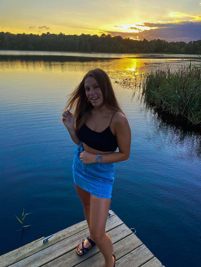 Madison poses in front of a lake. 