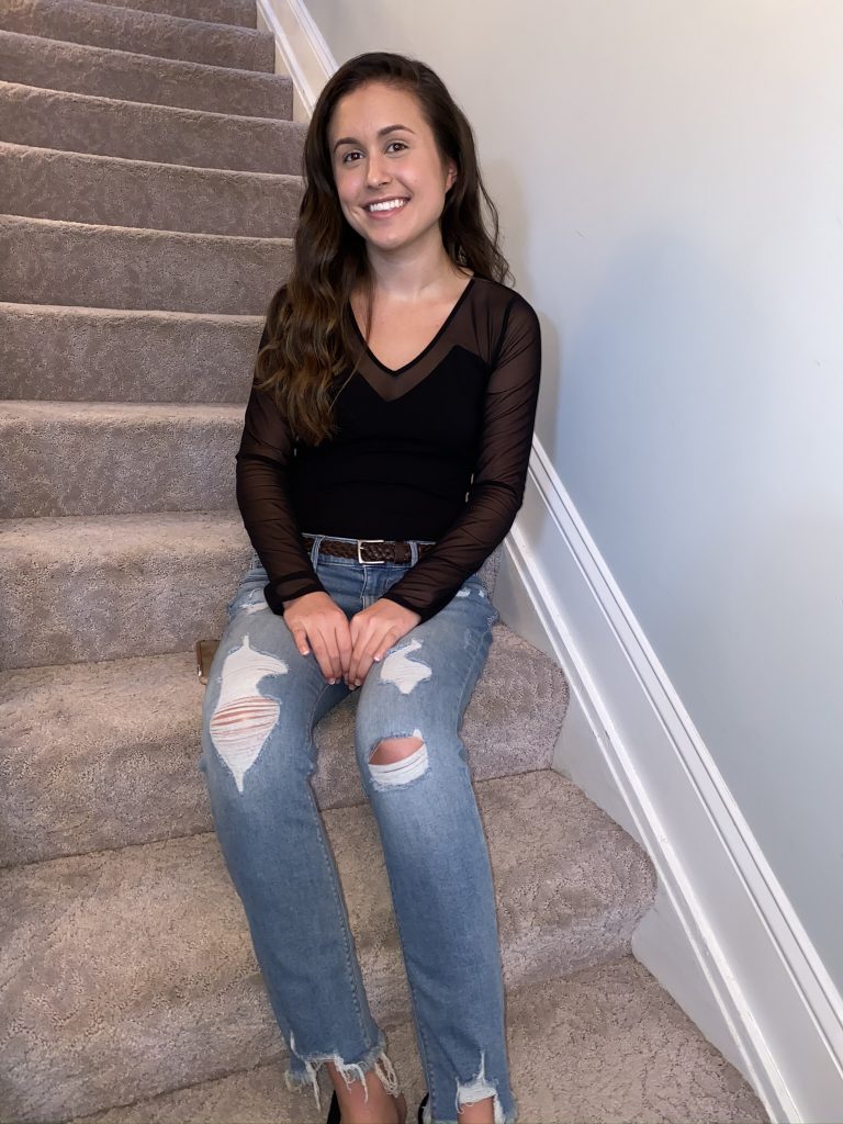 Mallory sitting on a set of stairs indoors.
