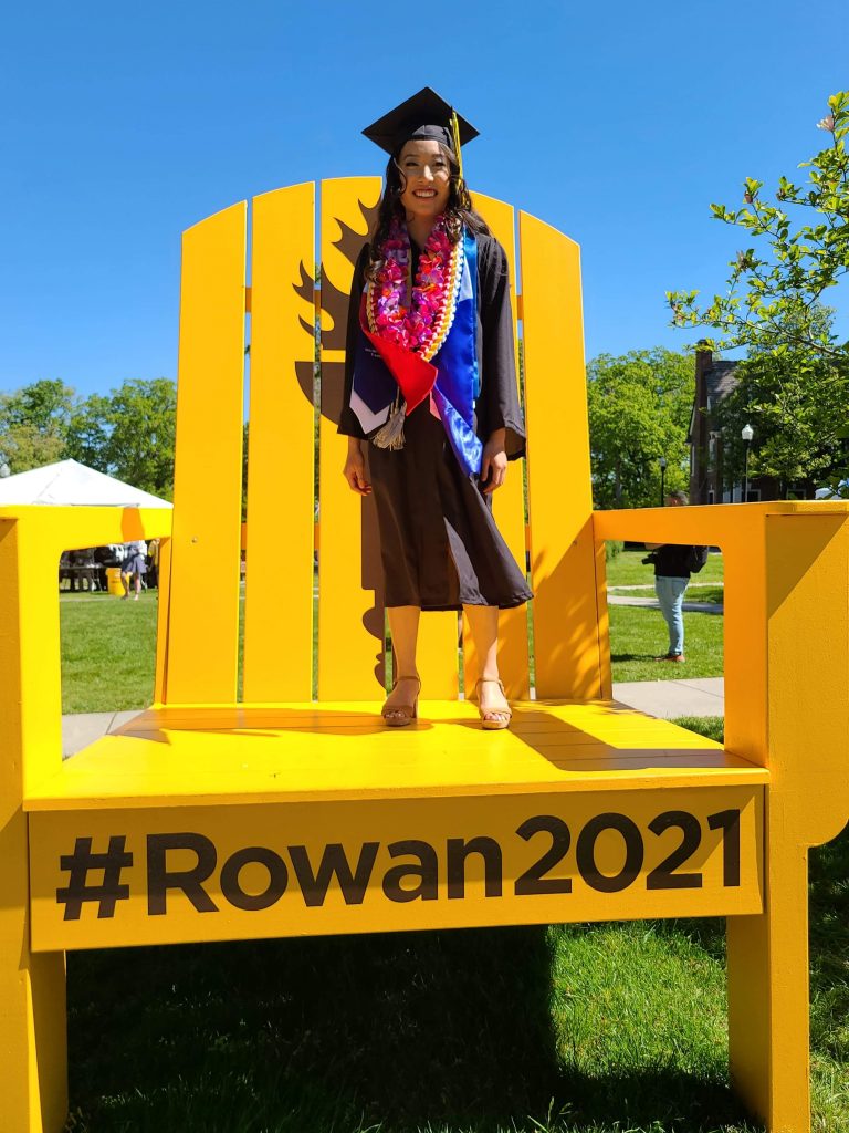 Marian stands on a big yellow chair that says #Rowan2021.