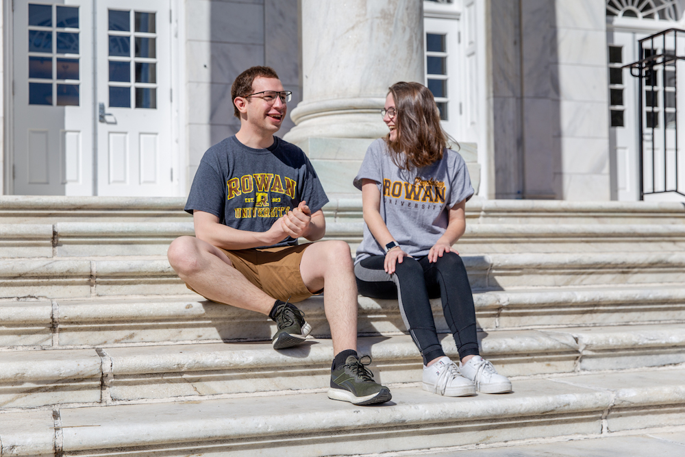 Kevin and Leah sit on the Bunce Hall marble steps both wearing Rowan t-shirts.