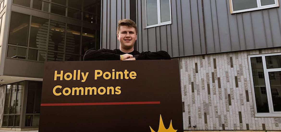 Mitch poses at the Holly Pointe Commons sign.
