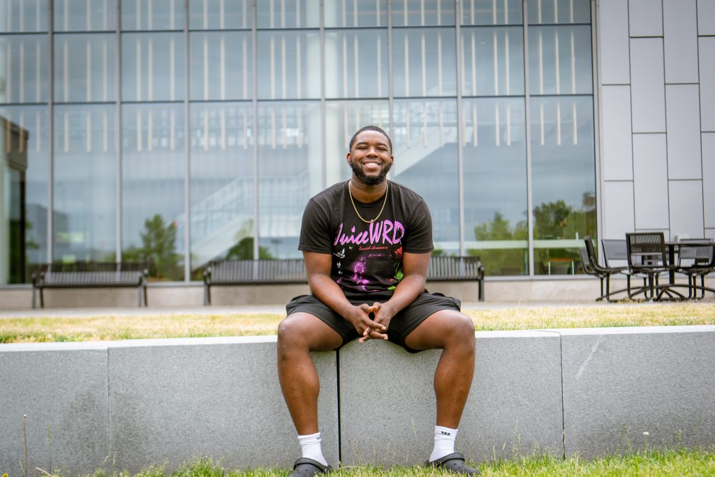 Reshaun sits on atop the concrete divider behind Business Hall.