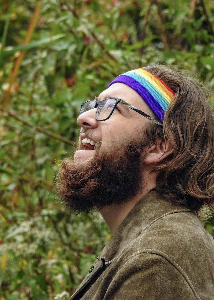 TJ smiling while wearing a rainbow headband.
