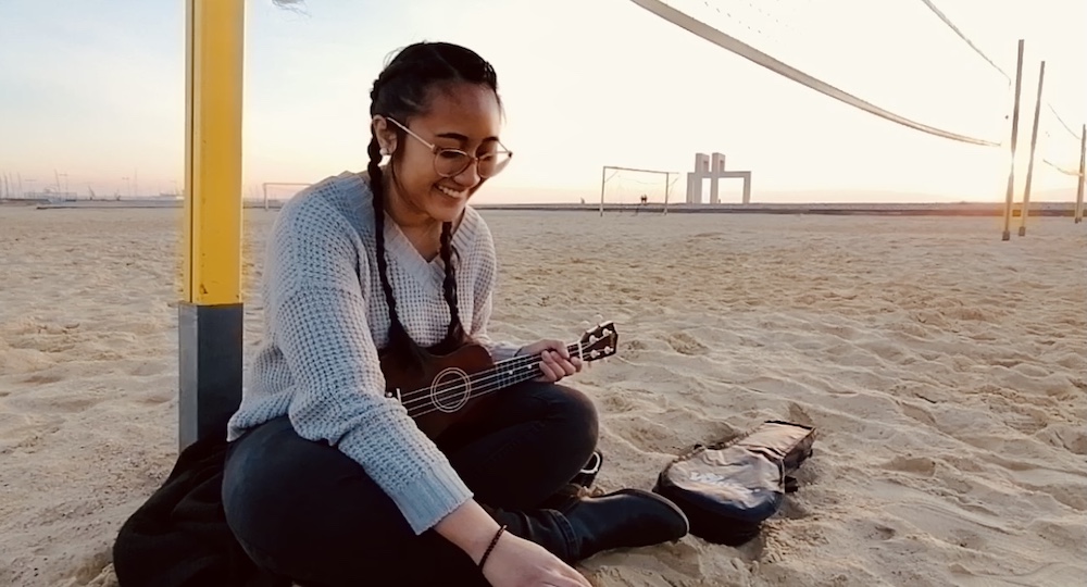 Stephanie plays a ukelele while sitting on a beach in Le Havre, France.