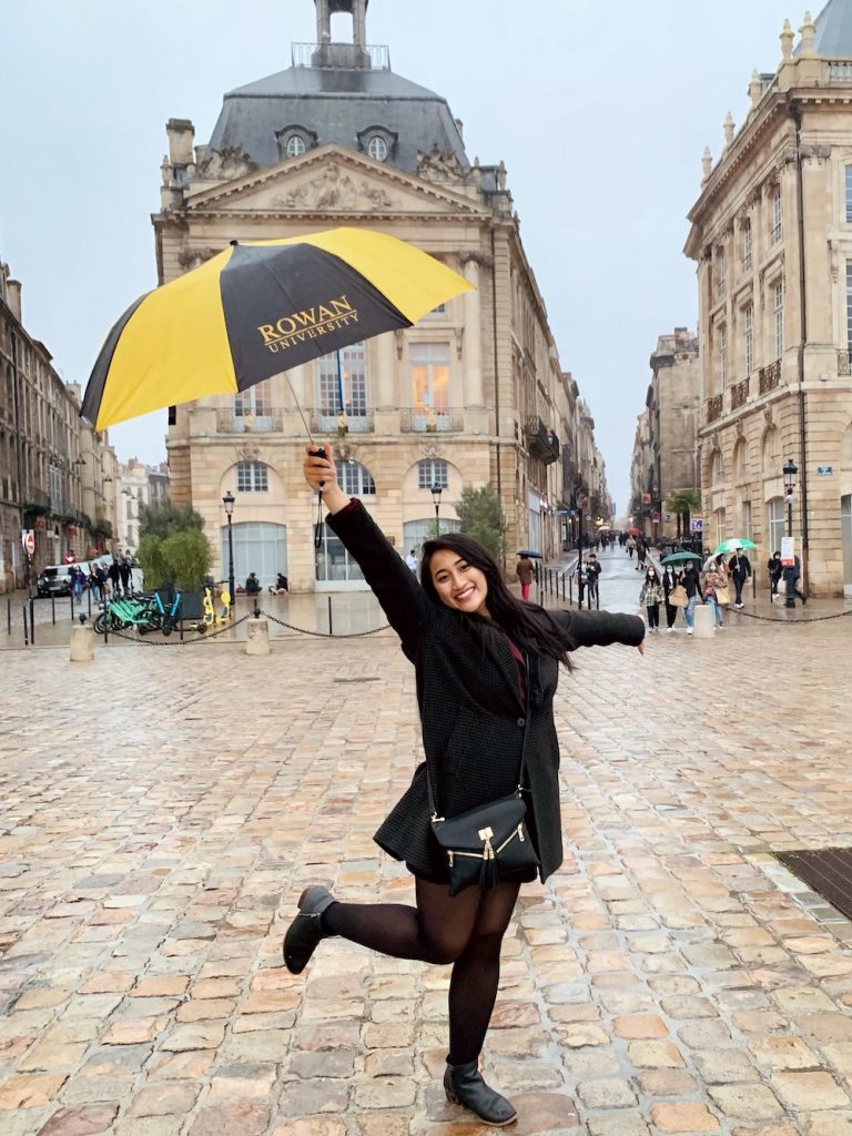 Stephanie poses happily while holding a Rowan umbrella in the air in France.
