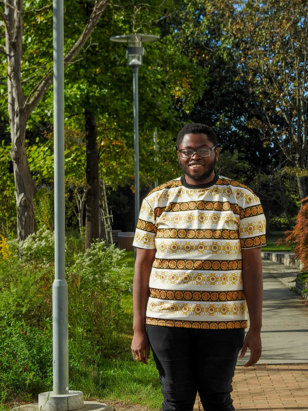 Denzell smiling and posing for a photo outside the engineering trail.