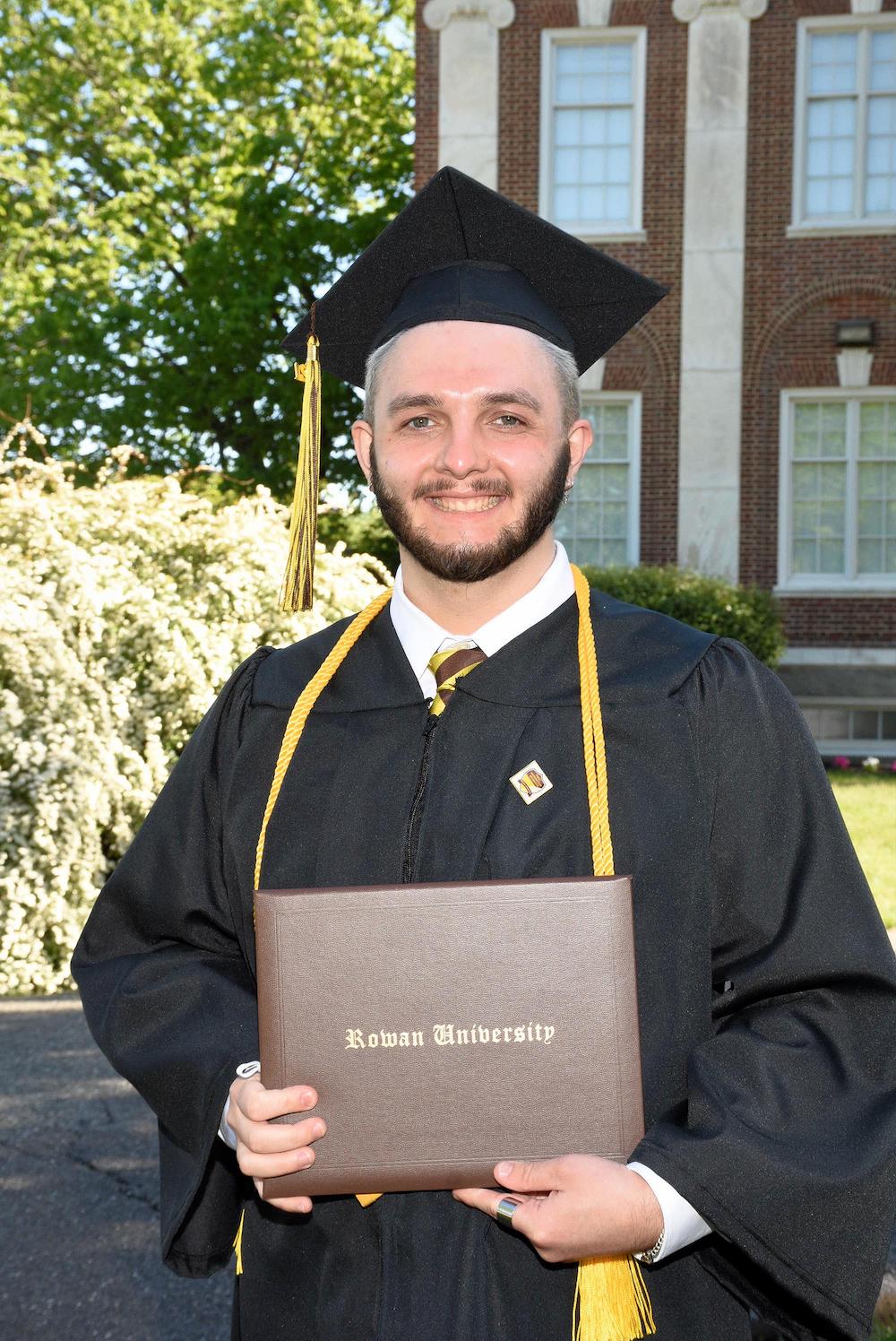 Scott holds his diploma at commencement.