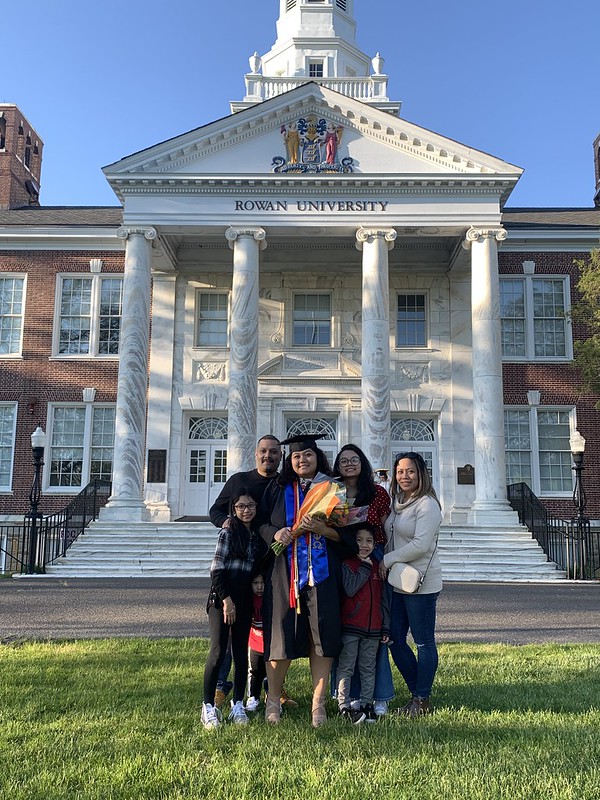 A graduate poses with her family in front of Bunce Hall.