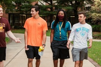 Five students walk and talk on campus.