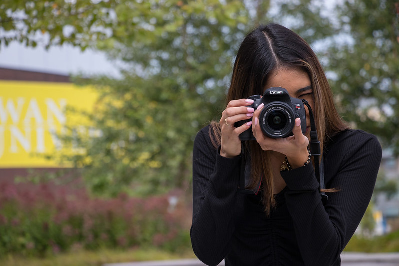 Student holds a DSLR camera in front of Wilson Hall.