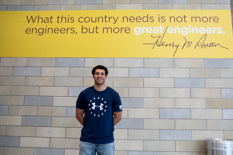 Brandon stands next to a Henry Rowan quote.