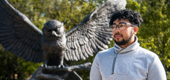 Neiloy stands in front of the Rowan prof statue.
