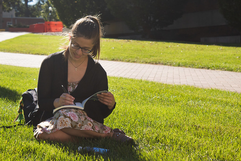 Brianna journals on the lawn by the Campbell Library.