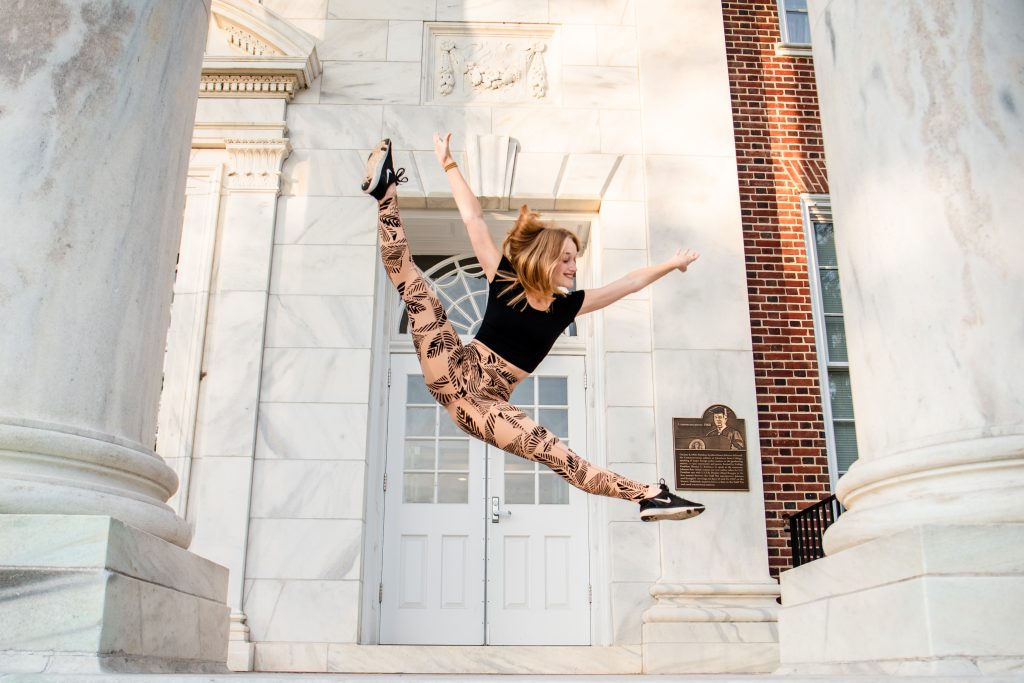 Dance and theatre major Kaya leaps in the air near an entrance of Bunce Hall.