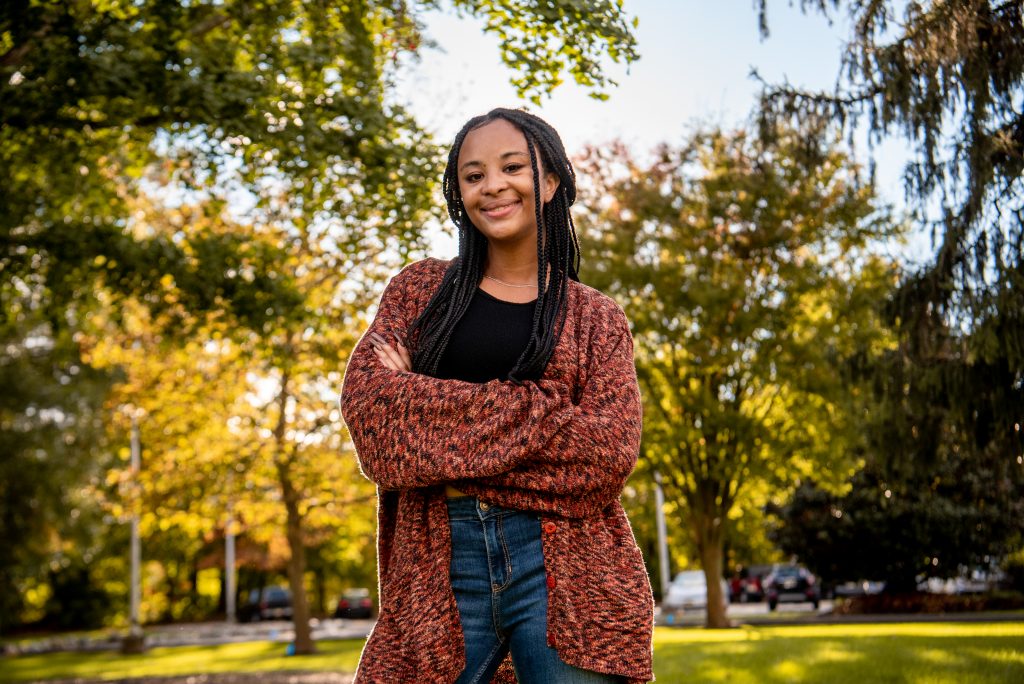 Samaria poses in front of trees on campus.