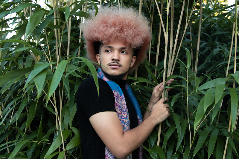 Sincere poses in front of some leafy green plants.