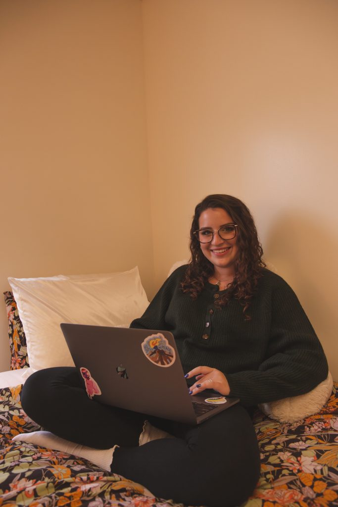 Missy poses for a photo as she sits in her dorm working on her laptop