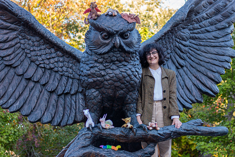 Emily Ward smiling next to Owl Statue with their beanie baby collection.