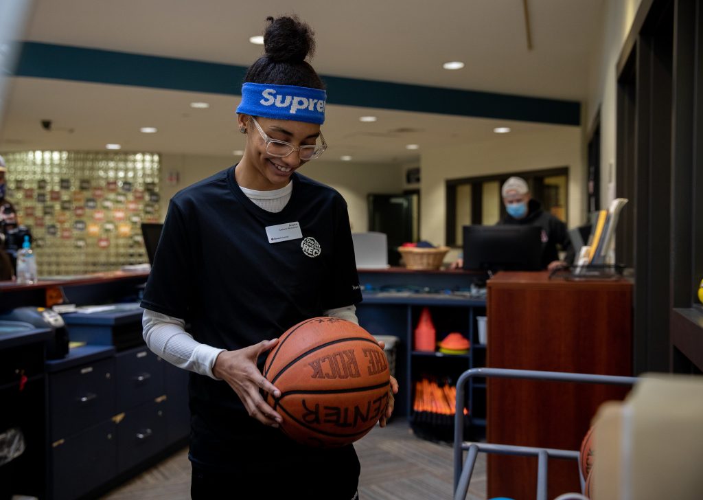 Jessica gets ready to check out a basketball to student at the front desk