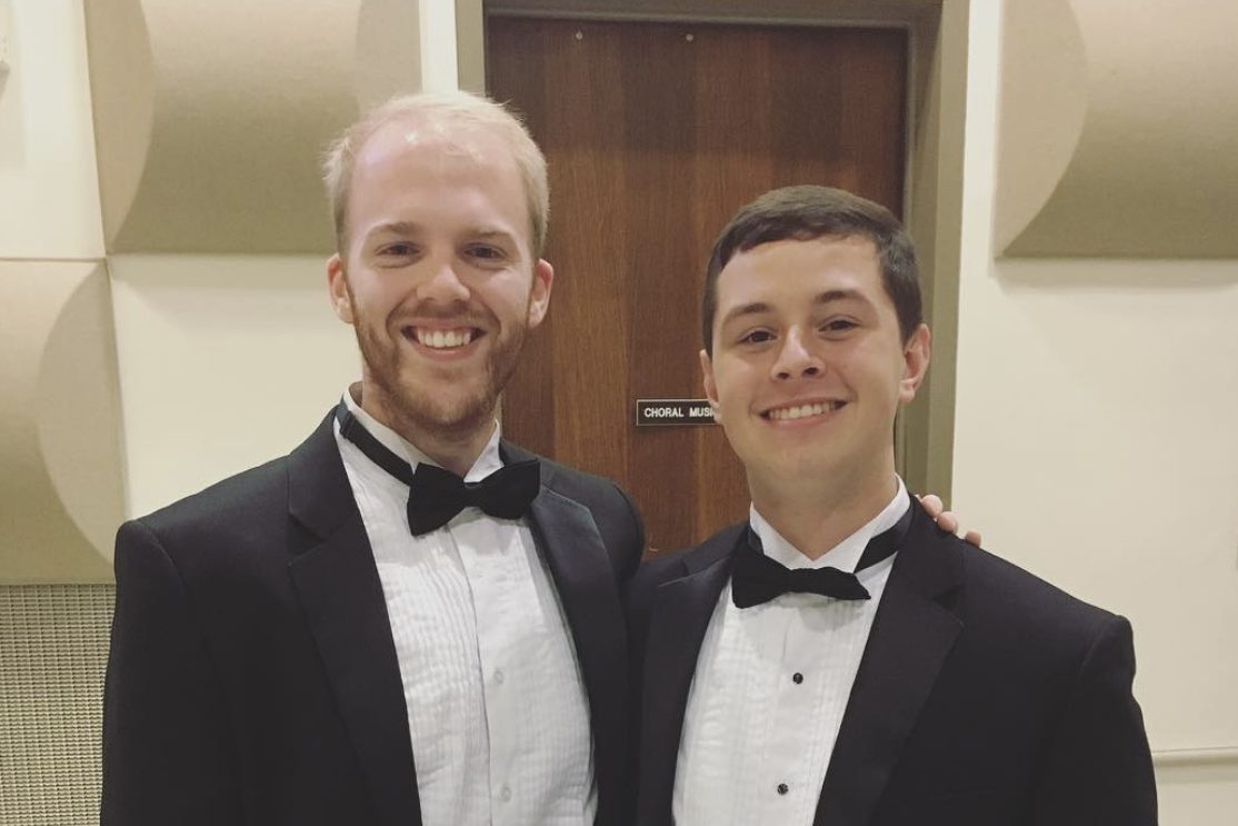 Kevin and Scott are standing in a studio room in Wilson Hall, wearing suits, and smiling.