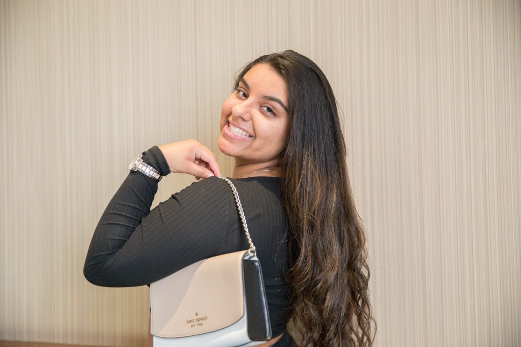 Riya Bhatt posing with purse looking over her shoulder.