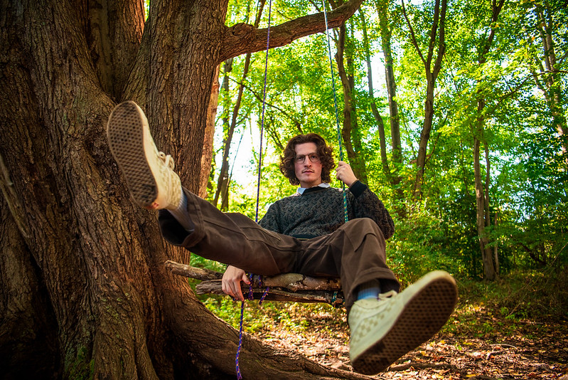 Brandon Simon is sitting on swing in the forest.