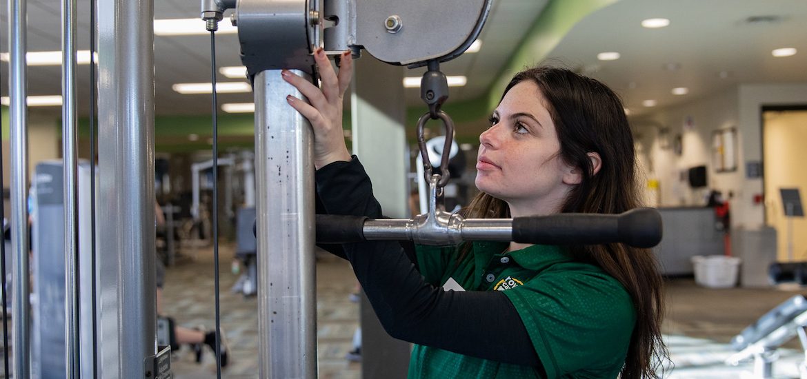 Rec Center student worker checks on gym equipment in one of the fitness rooms.