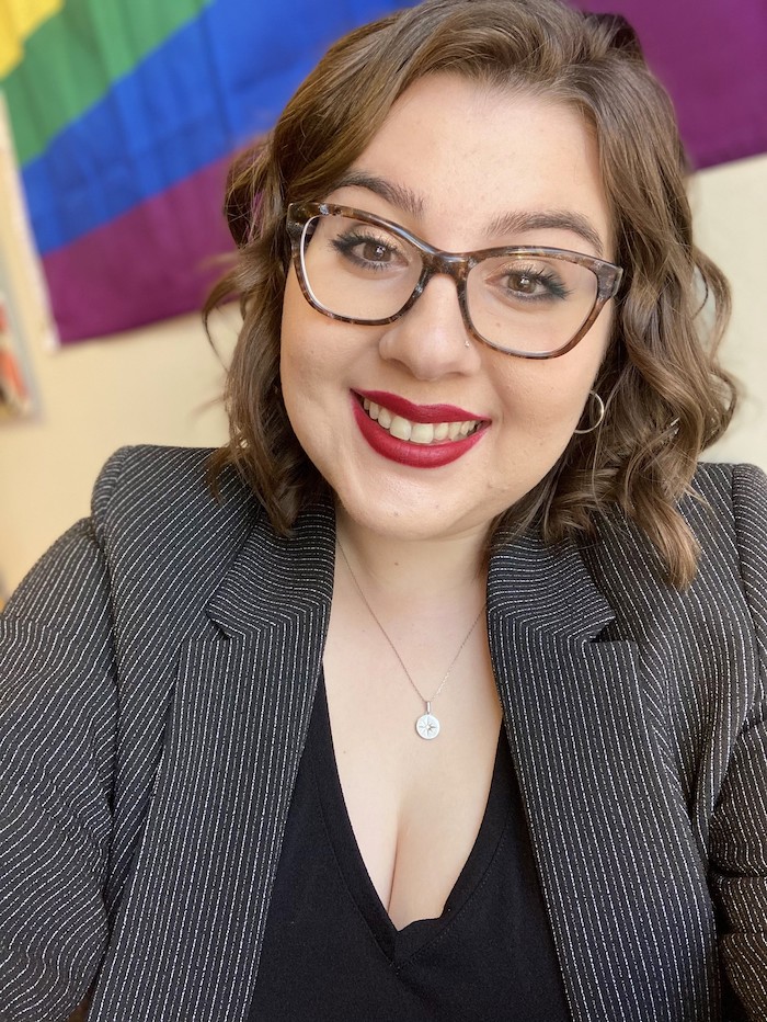 Ella Emmer headshot in front of a PRIDE flag.