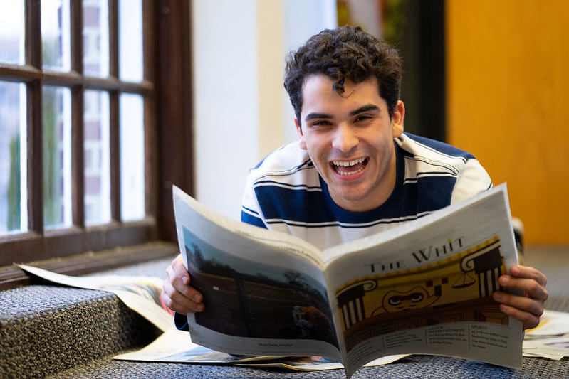 Joel Vazquez-Juarbe laughing while holding The Whit newspaper.