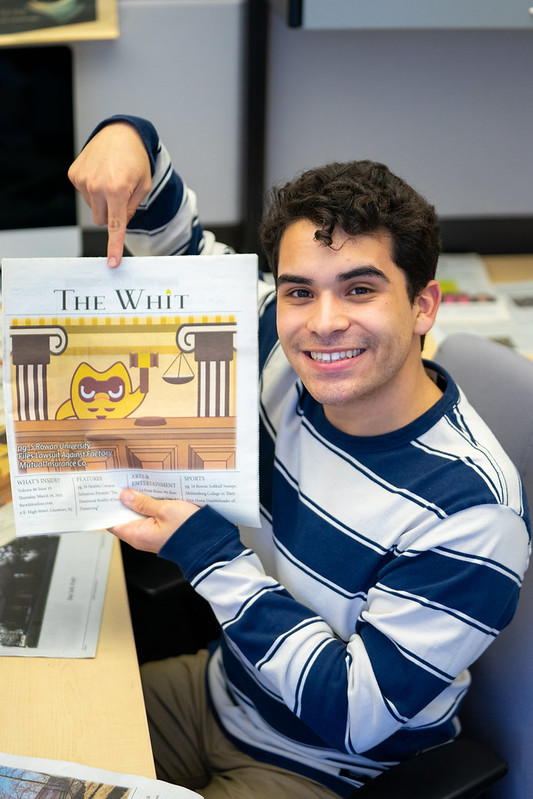 Joel Vazquez-Juarbe smiling and pointing at The Whit newspaper.