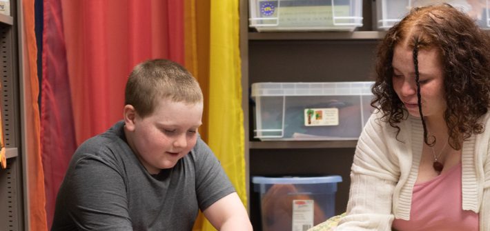 Gabriella Lugo is diligently working with a student in a classroom.