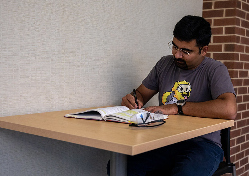 Amit studies at a desk in an academic building on campus.