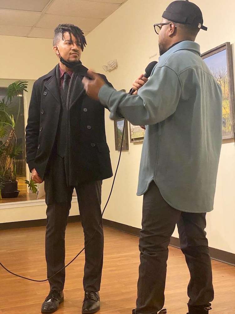 Isaiah interviews a subject in an art gallery.