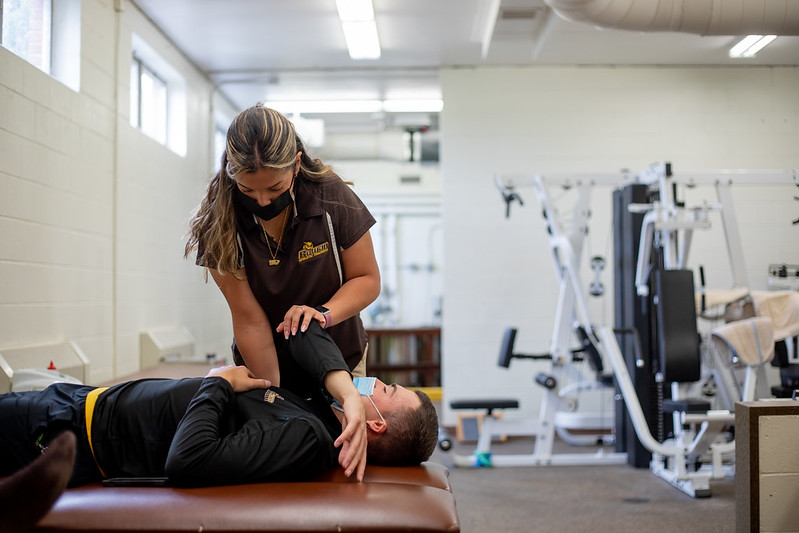 Samantha Santos stretching out a baseball player's shoulder.