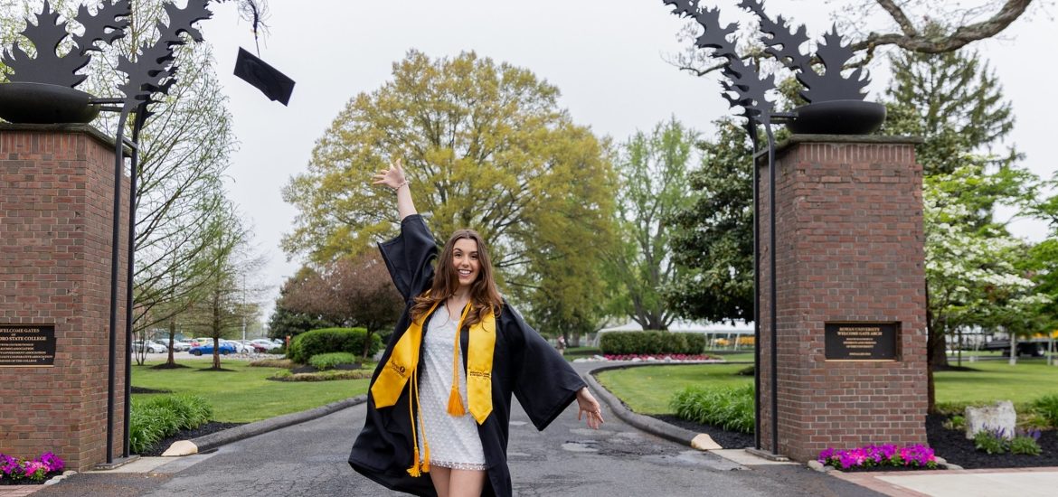 Loredonna throws her cap up in the air in front of the Rowan arch.