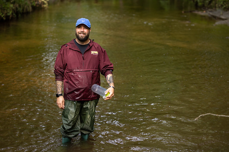 Zachary Rouhas wearing waders and taking measurements in Tall Pines Preserve water. 