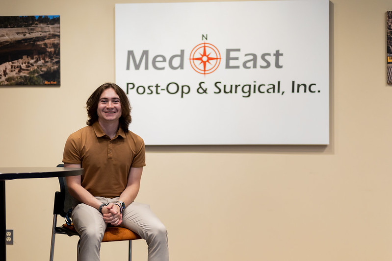 Dominic poses in front of a MedEast sign, where he interns.