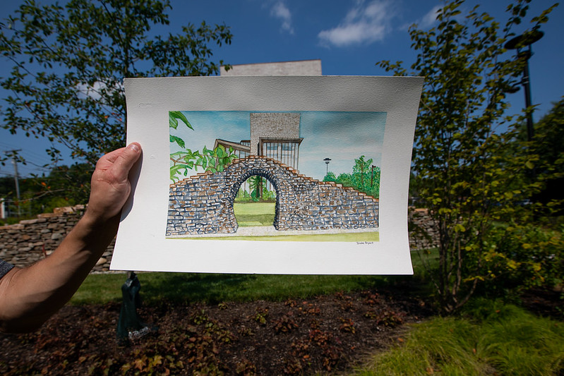 Brooke's watercolor of the Time Sweeps installation is held in front of Discovery Hall.