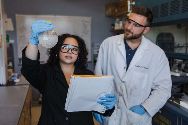 Biological Sciences major Aryana Marquez observes a lab experiment with another student.