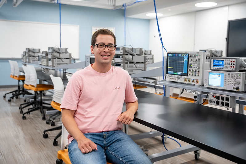 Jack Campanella smiles and sits in an Engineering lab on campus.