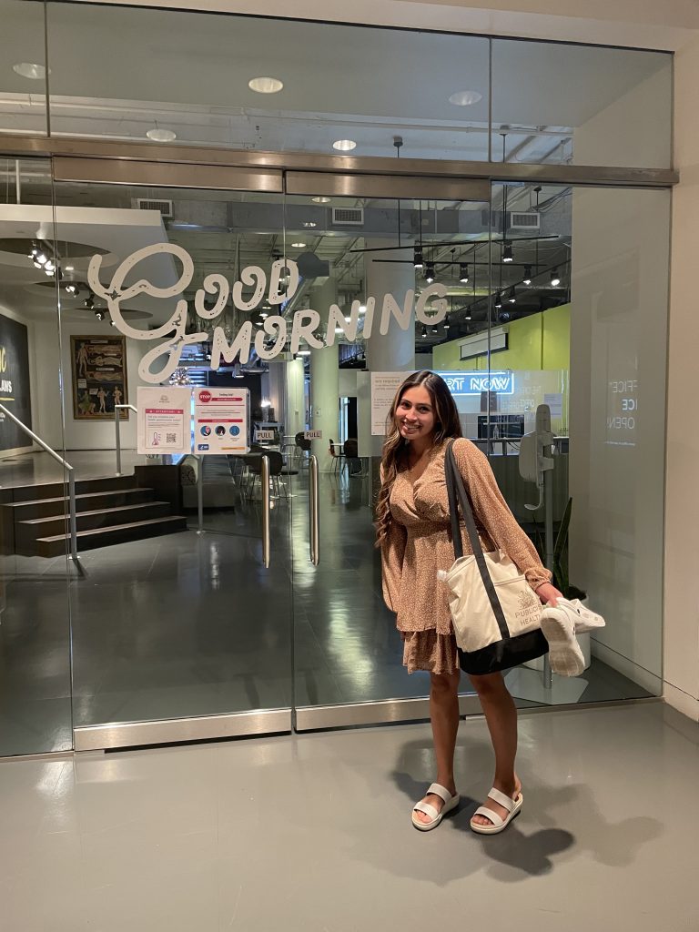 Angie poses indoors next to a sign which reads "Good Morning".
