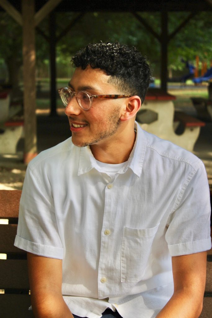 Jacob sits on a bench looking optimistic.