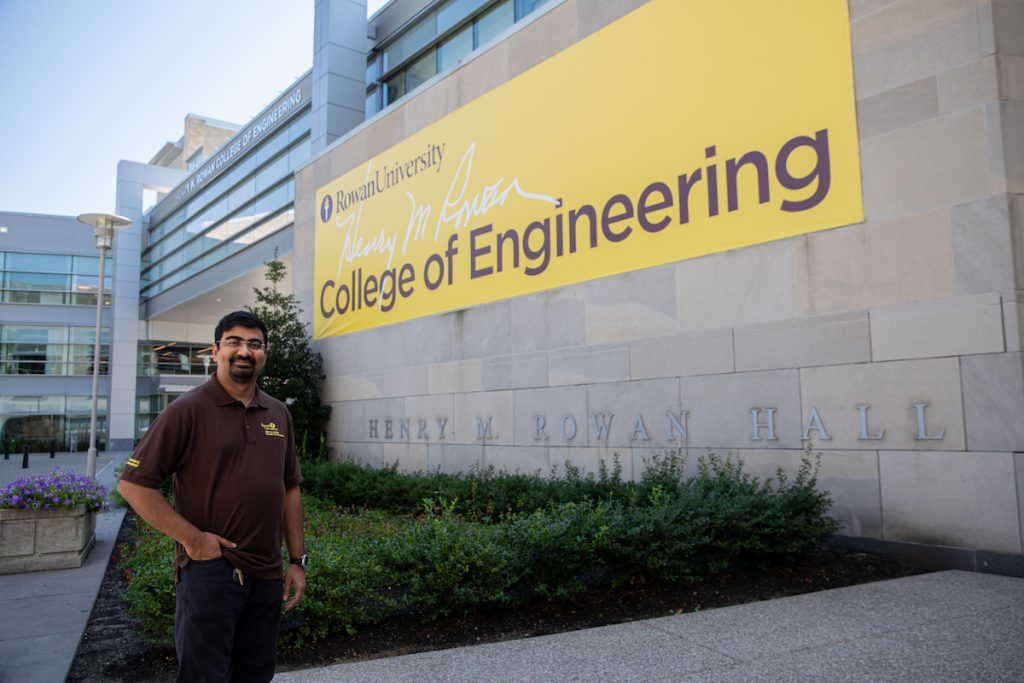 Amit standing in front of the College of Engineering banner.