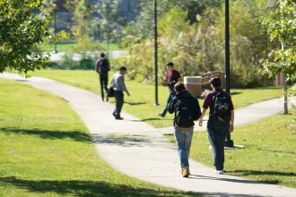 Students walking on a grassy path behind Wilson Hall.