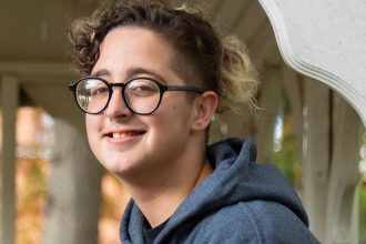 Rowan University Law and Justice major Kye inside a gazebo with fall leaves in the foreground.