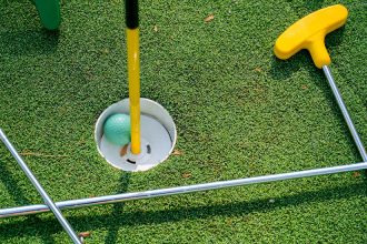Stock image of mini golf clubs, a ball and course hole.