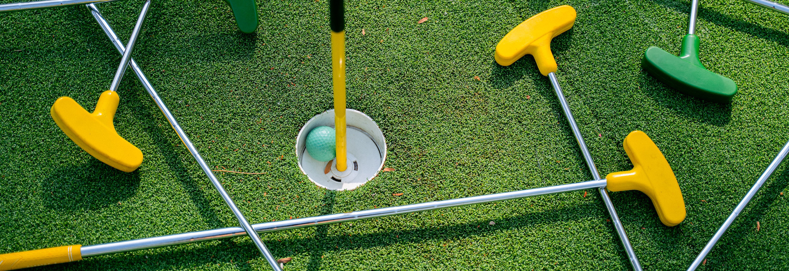Stock image of mini golf clubs, a ball and course hole.