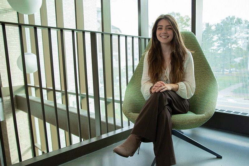 Rowan University Supply Chain and Logistics major Alivia sits in a chair in Discovery Hall.